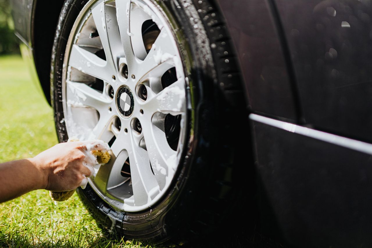core-values Detailed shot of a car wheel being cleaned at home in a sunny outdoor setting.